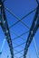 Low angle view on isolated symmetrical industrial steel bridge deck against blue sky with cross struts and metal beams