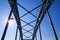 Low angle view on isolated symmetrical industrial steel bridge deck against blue sky with cross struts and metal beams, sun burst