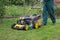 Low angle view of man pushing lawnmower through small backyard in spring