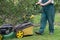 Low angle view of man pushing lawnmower through small backyard in spring