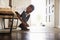 Low angle view pre-teen black boy tying his shoes before leaving home, selective focus