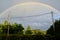 Low-angle view of a rainbow arch over the botanical plants and electricity wires