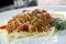 Low angle view of a serving of Italian spaghetti with a meat based bolognese, or bolognaise, sauce on a plain white plate