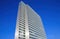 Low angle view on silver bright skyscraper facade with countless windows against deep blue cloudless sky