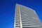 Low angle view on silver bright skyscraper facade with countless windows against deep blue cloudless sky