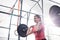 Low angle view of smiling woman lifting barbell in crossfit gym