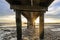 Low angle view of sun setting over ocean and timber pier