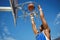 Low angle view of teenager hanging on basketball hoop