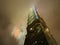 Low-angle view of a towering skyscraper shrouded in fog in Taipei at night.