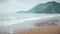 Low angle view tracking shot of a sandy sea shore with waves and sea foam