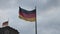 Low angle view of two German national flags waving in wind. Shot against overcast sky at dusk. Berlin, Germany