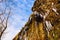 Low angle view up icicles on cascade in spring with birds fly back home background.