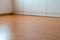 Low angle view of wooden laminate flooring in a bright spacious room with wall-to-wall closet