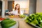 Low-angle view of young redhead woman cutting fresh yellow bell pepper preparing food salad sitting at table in modern