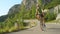 LOW ANGLE: Young male road cyclist speeding downhill through the sunny forest