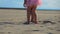 The low-angled shooting of legs of a little boy and girl walking along the beach