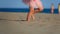 Low-angled shooting of legs of a little girl in pink running on the beach