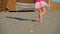 The low-angled shooting of legs of little girl in pink runnung on the beach