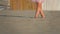 The low-angled shooting of legs of a little girl in pink walking in the sand