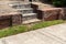 Low brick retaining wall with concrete block stairs, recent tuckpointing, green grass and sidewalk