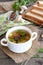 Low calorie soup with mushrooms, potatoes, carrots and parsley. Pieces of bread, spoon, parsley, fresh agaricus on a wooden table