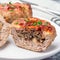Low carb paleo meat cups, stuffed with champignons, bacon and cheese, garnished with green onion, on  plate, square format,