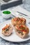 Low carb paleo meat cups, stuffed with champignons, bacon and cheese, garnished with green onion, on  plate, vertical