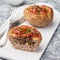 Low carb paleo meat cups, stuffed with champignons, bacon and cheese, garnished with green onion, on a white plate, square format