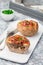 Low carb paleo meat cups, stuffed with champignons, bacon and cheese, garnished with green onion, on  white plate, vertical