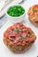 Low carb paleo meat cups, stuffed with champignons, bacon and cheese, garnished with green onion, on  white plate, vertical,