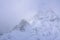 Low cloud of a snowstorm slowly crowling over snow blanketed peaks of Mt Ruapehu. Stunning winter landscape of Tongariro