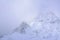 Low cloud of a snowstorm slowly crowling over snow blanketed peaks of Mt Ruapehu. Stunning winter landscape of Tongariro