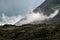 Low clouds, changeable weather in the mountains. Scenic alpine landscape with gray low clouds and sunlight