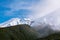 Low clouds lifting over mountain ridge and snow covered peaks. Natural background