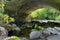 Low Creek on a Rocky Path Under the Arch of an Old Stone Bridge