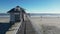 Low drone view going along the beach directly over a wooden pier from one side to the other