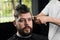 Low fade machine haircut for handsome bearded man in barbershop. Hair cut with a smooth transition.