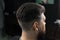 Low fade machine haircut for handsome bearded man in barbershop. Hair cut with a smooth transition.