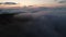 Low key aerial view evening flight over clouds and hills in the mountains at blue hour after sunset. The concept of