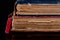 Low key closeup of very old books in poor condition on black background.