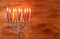 Low key image of jewish holiday Hanukkah background with menorah Burning candles over wooden background