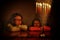 Low key image of jewish holiday Hanukkah background with two cute kids looking at menorah traditional candelabra