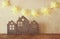 Low key image of vintage wooden house decor on wooden table and stars garland. retro filtered. selective focus