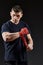 Low key studio portrait of handsome muscular fighter preparing for boxing on dark blurred background