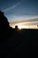 Low key view of a camper van in silhouette parked on top of a mountain at sunrise