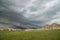 A low and ominous shelf cloud approaches rocky bluffs on a hillside.