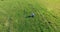 Low orbital flight around man on green grass with notebook pad at yellow rural field.