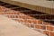 Low parapet made of red and dark red bricks beside brick pavement