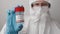 Low quality Covid 19 vaccine bottle in doctors hand. Doctor in protective suit, face mask, safety googles and rubber