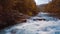 Low rapid flight over the rushing mountain river and waterfall, blue in the middle of the forest and mountains. Sunset